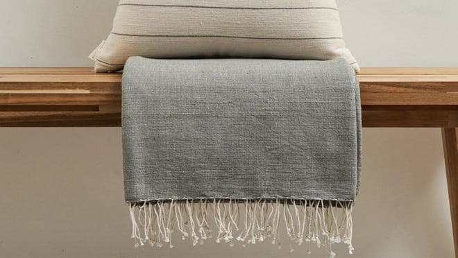 A beige pillow and a gray blanket.