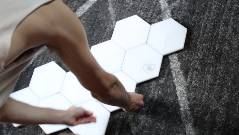 Person assembling Govee hexagon lights on floor.