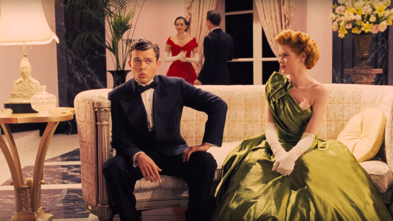 Actor Alden Ehrenreich sits on a couch opposite Natasha Bassett in a scene (depicting a fifties Hollywood movie set) from the Coen Brothers comedy Hail Caesar.