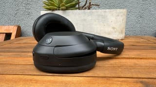 The Sony Ult Wear headphones in black, sitting on a wooden table with a planter in the background.