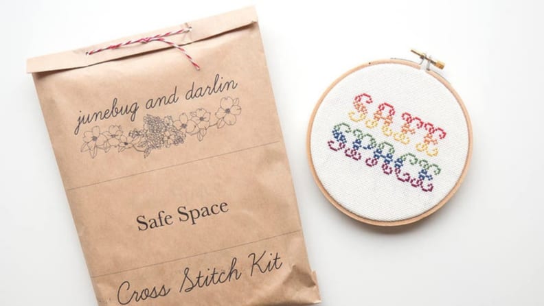 Cross stitch kit next to a cross stitch that says "Safe Space" in rainbow colors