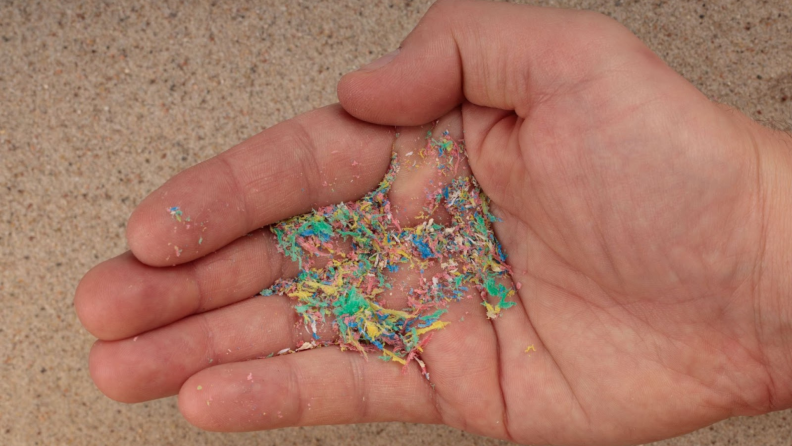 A hand holds microplastic bits in its palm.