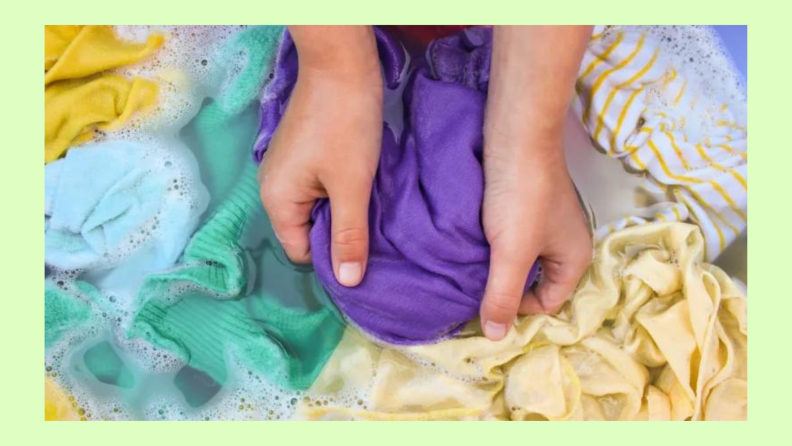 Hands washing clothes in soapy water