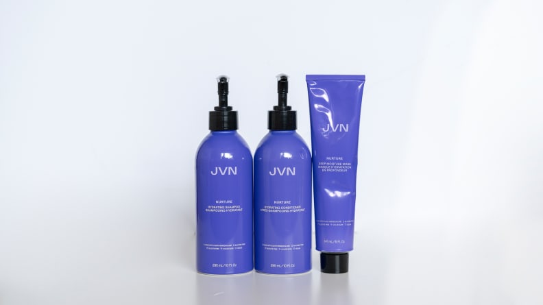 Two purple pump bottles and one purple squeeze tube stand in a line.