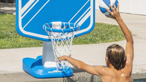 A kid playing basketball in the pool.