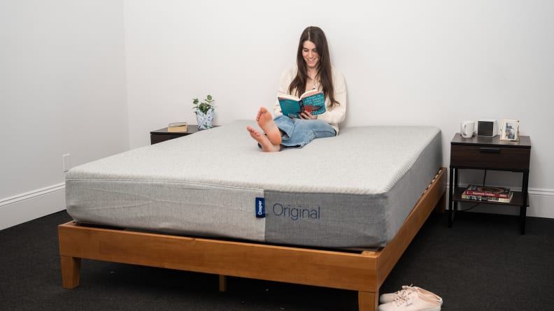 a person sits and reads on the casper original mattress