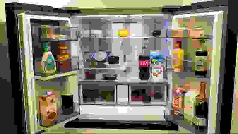 The fridge doors wide open, revealing all sorts of food and condiments inside.