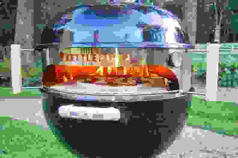 The Kettle Pizza in a Weber grill with open flame.