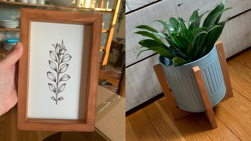 a black and white floral print inside a wooden frame, and at right, a plant grows inside a blue metal planter