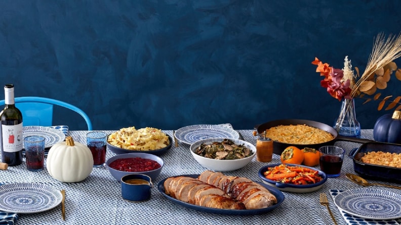 A table filled with Thanksgiving dishes, including turkey, carrots, cranberry sauce, and more.