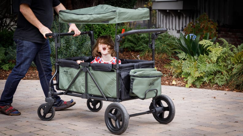 A man pushes a child in a Jeep stroller.