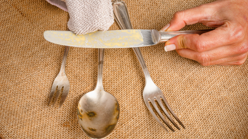 Person using towel to polish several pieces of silver.