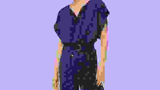 Navy blue jumpsuit with polka dots against a purple background