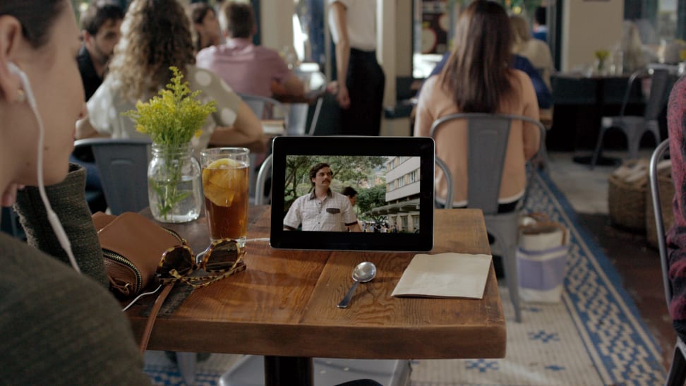 A person watching a Netflix show on their mobile device on a table