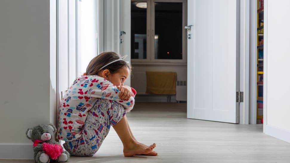 Little girl crouched in hallway with stuffed animal