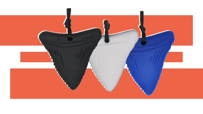 Three sensory chew necklaces in black, white, and blue hang side by side in front of a red-orange and white background.