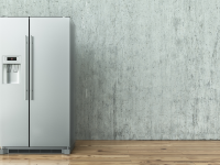 A free-standing refrigerator posed against a blank wall.