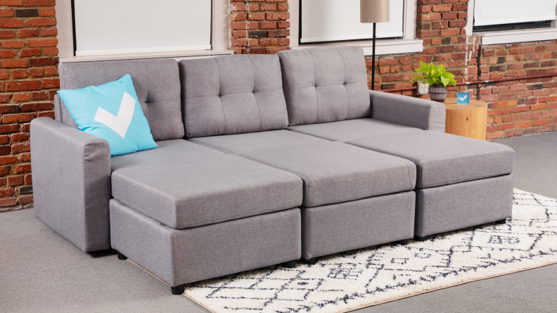 A gray upholstered couch with three ottomans to form a large daybed.