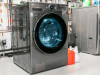 An LG washer-dryer combo in the Reviewed testing lab in front of a wall of copper pipes.