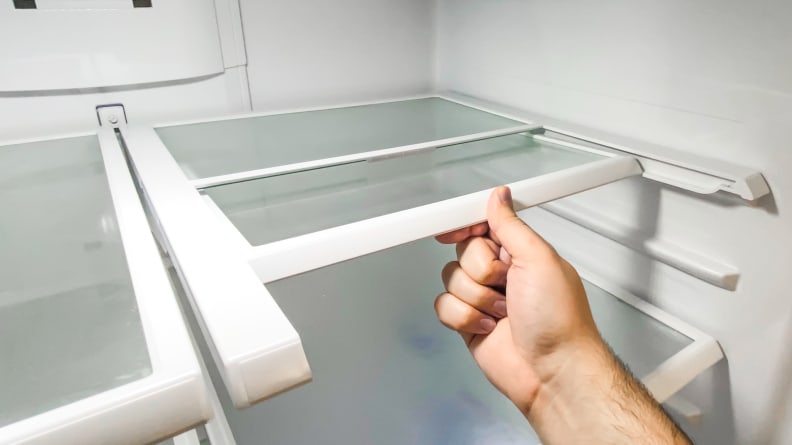 A shot of a hand folding the GE GNE27JSMAFSS French door refrigerator's flexible shelf back, to allow for larger items to be stored in front of it.