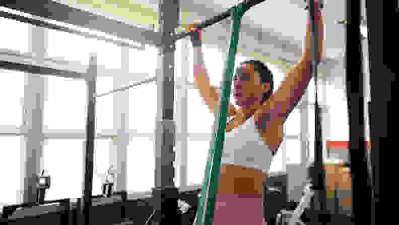 A woman doing an assisted pull-up.