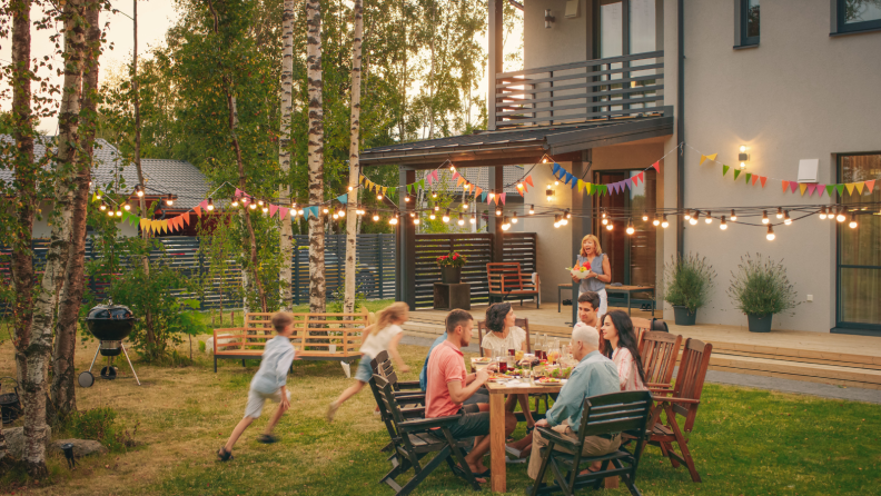 A backyard full of people with string lights hanging above.