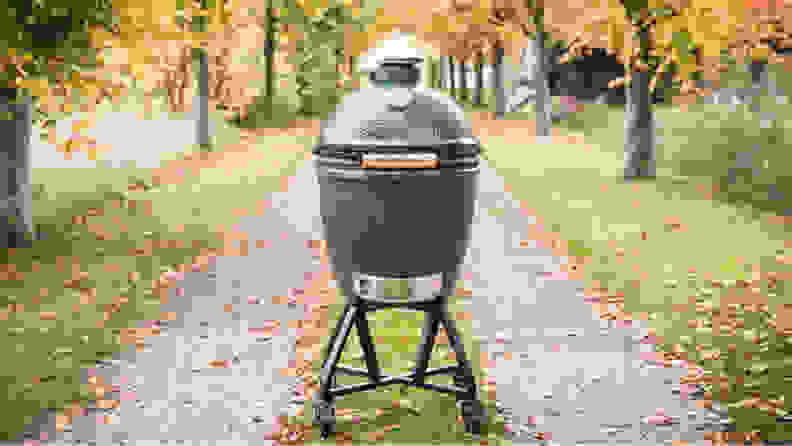 A Big Green Egg sits in the middle of a road surrounded by autumnal foliage.