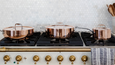 Copper cookware sits on a high-end gas stovetop.