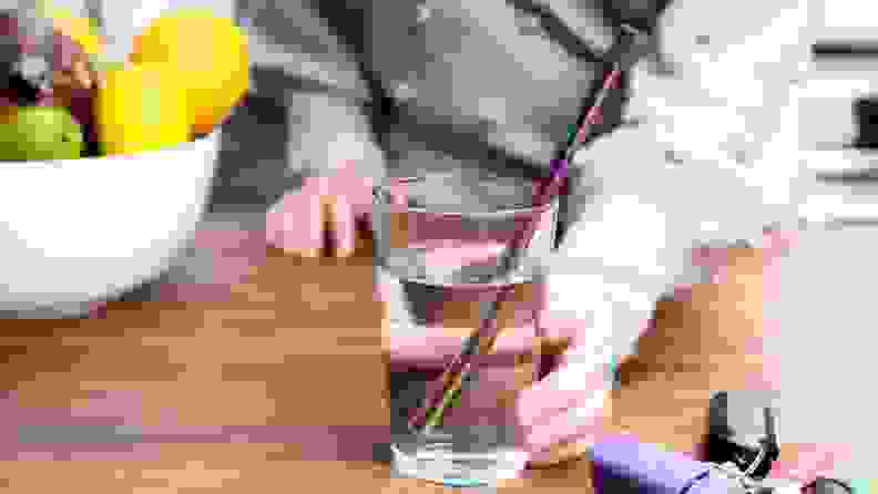 A person holds a glass with a reusable straw.