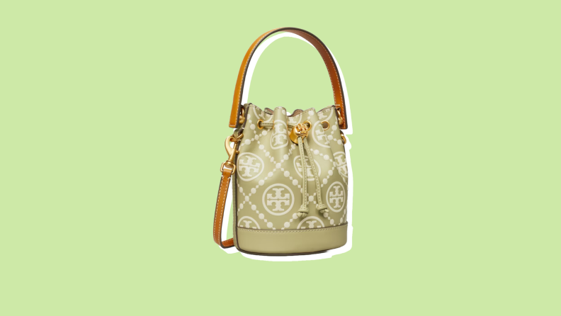 Photo of the Tory Burch T Monogram Mini Bucket Bag against a green background.