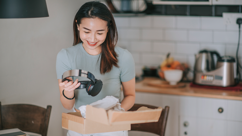 A woman takes a pair of headphones out of a box