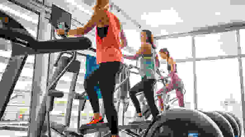 Three women using ellipticals.