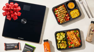 Factor prepared meals, snacks, and drinks displayed alongside a Withings smart scale, shown as part of a promotion using the Factor promo code.