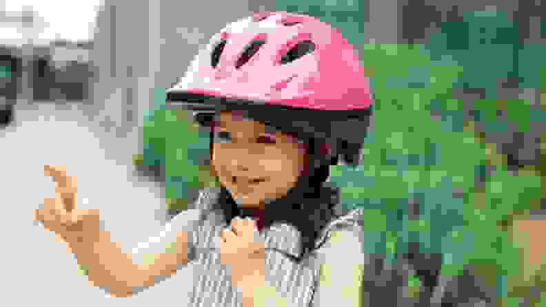 A little girl smiles with her pink Joovy helmet