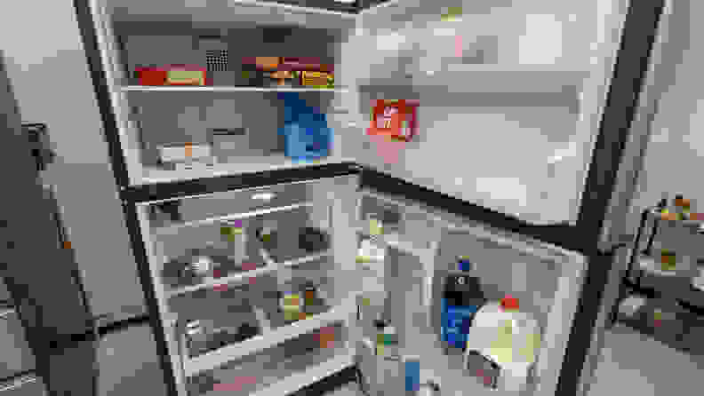 A shot of the interior of both the fridge and freezer compartments. The freezer compartment looks large, and the fridge compartment looks squat underneath it. Both compartments are stocked with food.