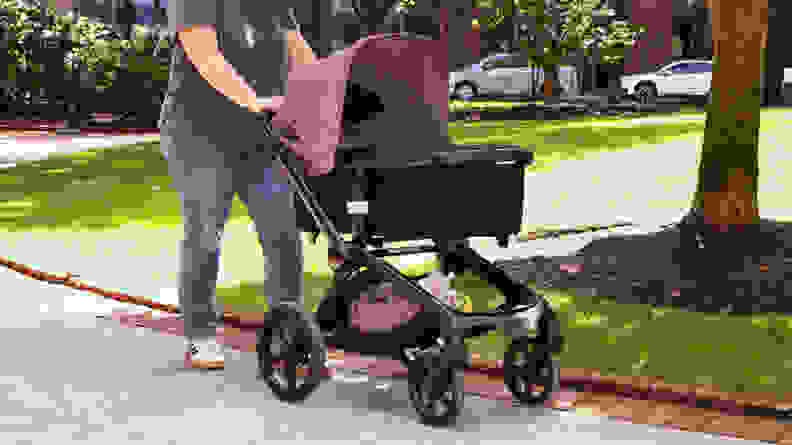 A woman walking in a park with the Bugaboo Fox 5 stroller in the color black.