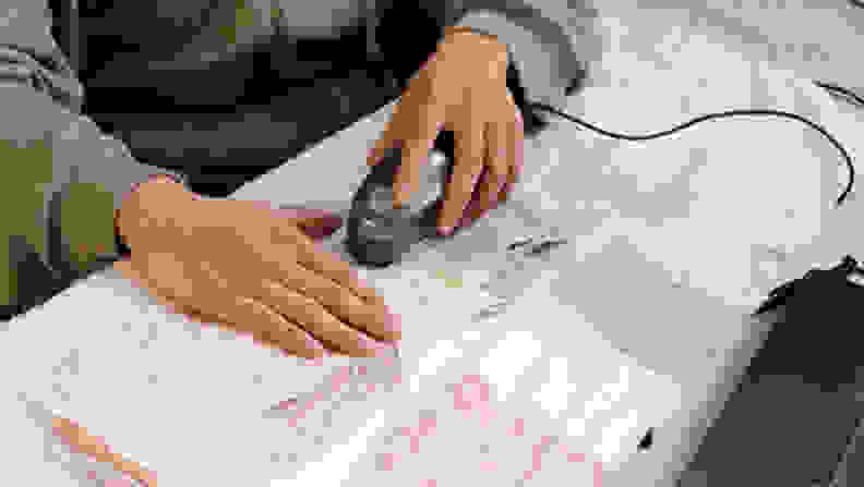 A tester uses a photospectrometer to measure stains on several washed stain strips.