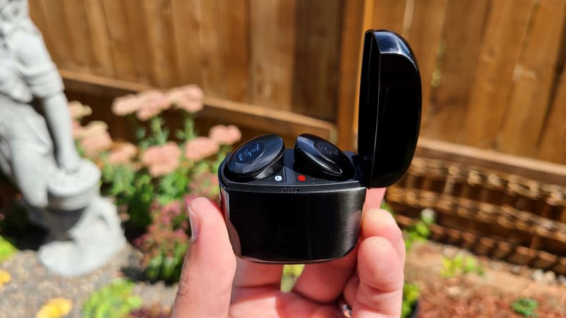 The black enameled Klipsch T5 II True Wireless ANC earbuds case is held open with the tops of the buds peaking out in front of a succulent garden.