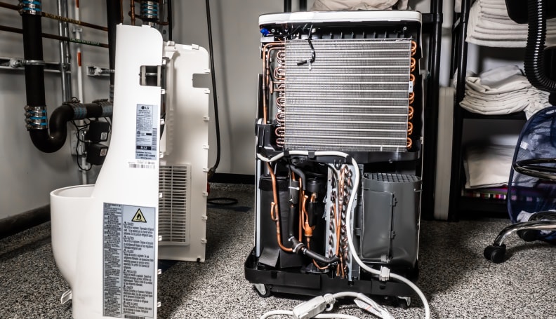An A/C is sitting on its side, with its casing fully removed and sitting beside it.