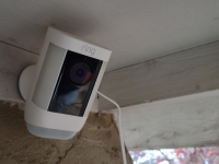 Product of mounted Ring Spotlight Cam Pro security camera on ceiling outside of home.