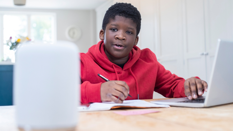 A boy does homework with a smart speaker.