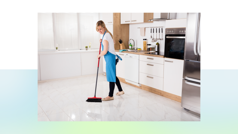 A person sweeps their kitchen with a broom.
