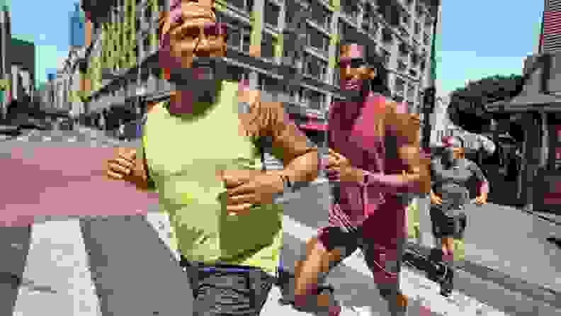 Two people running while happily wearing their Fitbit 6.