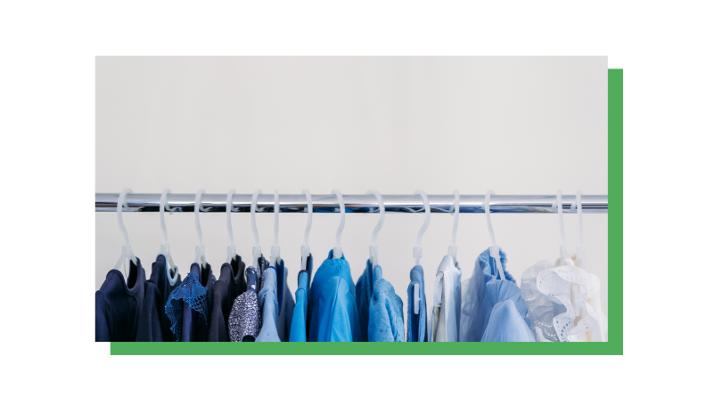 Blue shirts hang on a metal clothing rack.