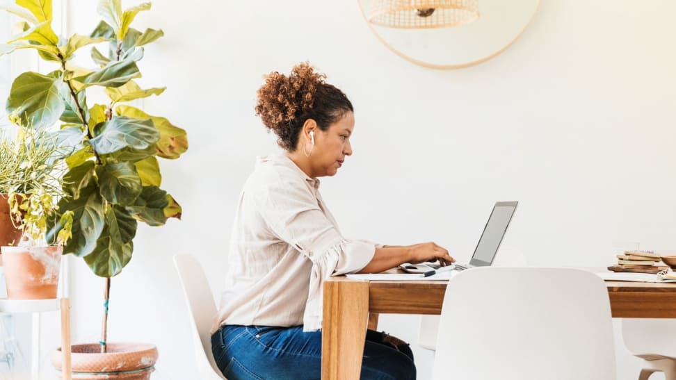 Woman sitting at dining table working on laptop