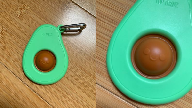 an avocado keychain with a brown pop-it as the pit