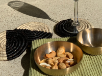 堪萨斯青铜碗和手工制作的棕榈叶杯垫，香槟杯和腰果放在绿色厨房亚麻布上