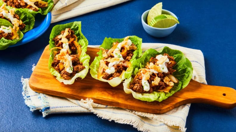 A wooden cutting board with prepared lettuce wraps.