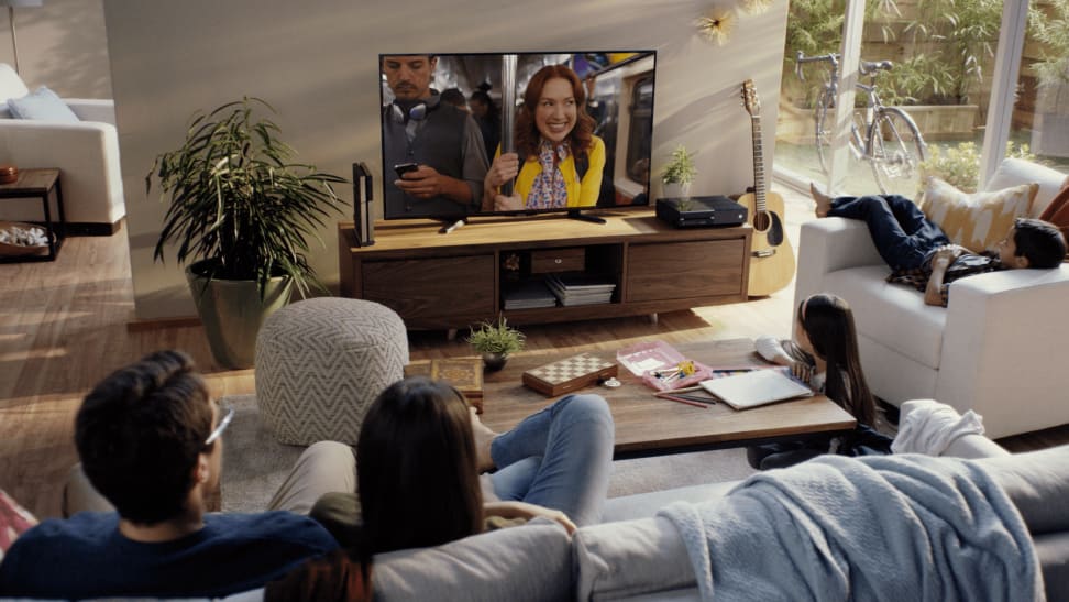 A group of people watching TV in a large living room.