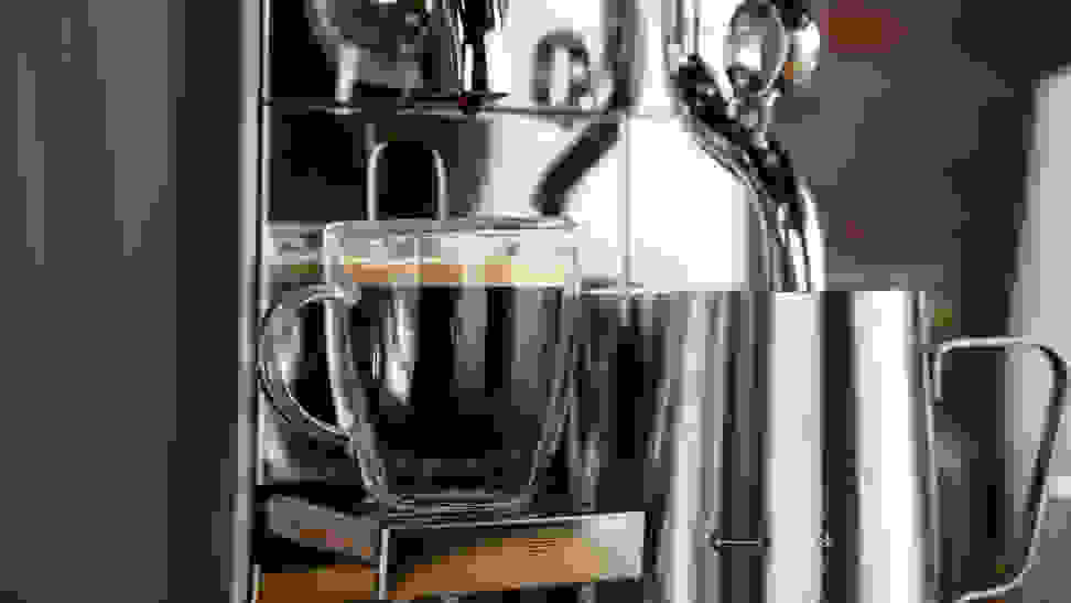 A close-up photo of the Breville Nespresso Creatista brewing an espresso shot and frothing milk.
